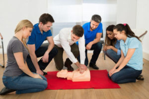 Practicing CPR On Emergency First Aid At Work Course